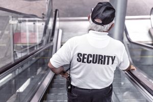 Security guard on escalators, wearing cap, offering security