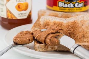 peanut butter on a knife being put on toast